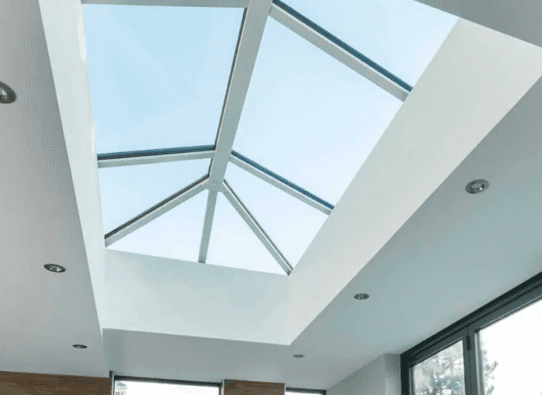 Modern room with large geometric skylight and white walls, showcasing natural light and minimalistic design.